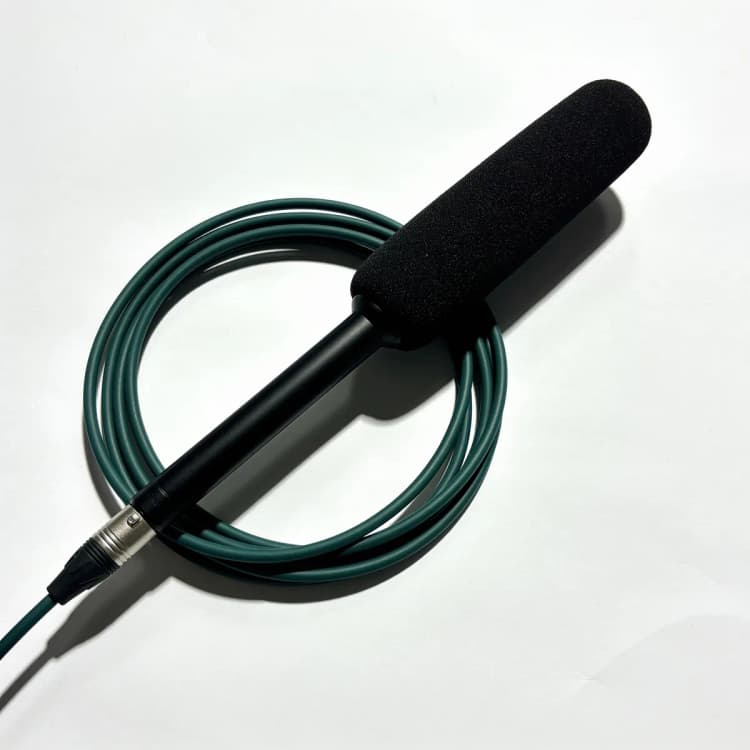 A shotgun microphone resting on a coiled forest-green cable